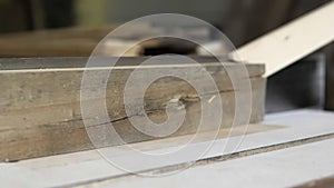 Close-up: a carpenter in his workshop saws a wooden board with a circular saw, makes furniture parts in natural light. A