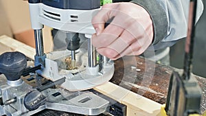 Close-up of a carpenter`s hand working with an manual electric cutter in a home workshop. Finishing wooden parts