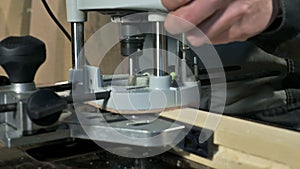 Close-up of a carpenter`s hand working with an manual electric cutter in a home workshop. Finishing wooden parts