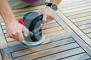 Close-up of carpenter`s hands working with electric sander