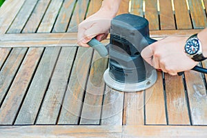 Close-up of carpenter`s hands working with electric sander