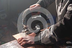 Close up of carpenter`s hands working power tools for processing wood. Power Jigsaw