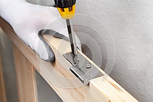 Close up of a carpenter screwed a hinge on a wooden plank