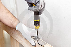 Close up of a carpenter screwed a hinge on a wooden plank