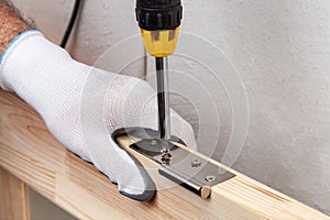 Close up of a carpenter screwed a hinge on a wooden plank