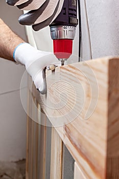 Close up of a carpenter screwed a hinge on a wooden plank