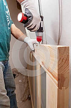 Close up of a carpenter screwed a hinge on a wooden plank