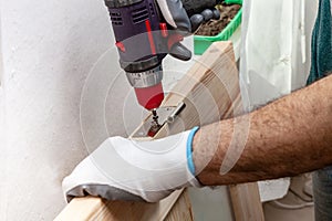 Close up of a carpenter screwed a hinge on a wooden plank