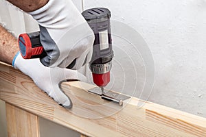 Close up of a carpenter screwed a hinge on a wooden plank