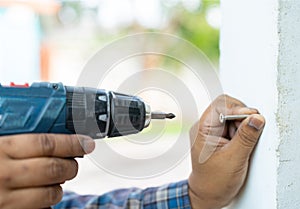 Close up the carpenter is screwing into pole using a cordless screwdriver