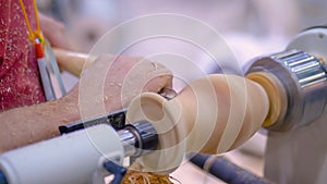 Close up: carpenter using chisel for shaping piece of wood on lathe