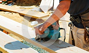 Close-up of a carpenter using a circular saw to cut a large board of wood
