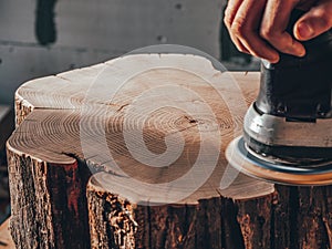 Close-up of a carpenter working with an electric grinder. wood stump processing photo
