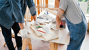 Close-up carpenters hands wearing work gloves draw the cutting line with a pencil on a wooden board. Construction industry,