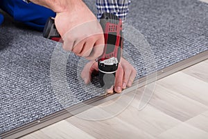 Carpet Fitter Installing Carpet With Wireless Screwdriver photo