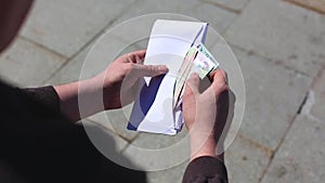 Close up of cash in envelope in hands. Money bonus in a paper envelope. A man holding an envelope with money. World