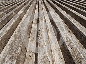 Close up of cast concrete with vertical ribbed texture with a converging view in sunlight and shadow