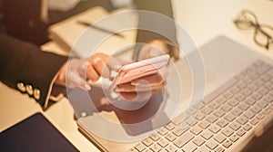 Close up of casual woman or freelancer working on laptop computer and holding mobile smartphone, working from home or casual