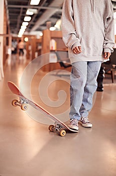 Close Up Of Casually Dressed Young Businesswoman With Skateboard Standing In Open Plan Workplace