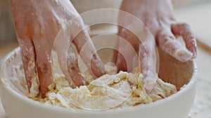 Close-up of caucasian child's female hands kneading sticky raw dough with fingers in bowl at home use wheat flour makes