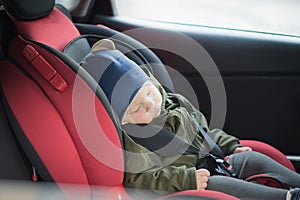 Close Up caucasian cute baby boy sleeping in modern car seat. Child traveling safety on the road. Safe way to travel