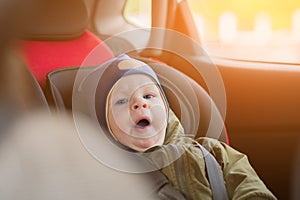 Close Up caucasian cute baby boy woke up and yawns in modern car seat. Child traveling safety on the road. Safe way to