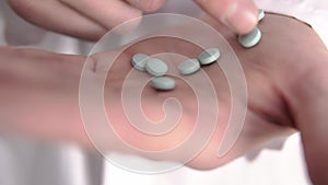 Close-up of Caucasian doctor's hand who is counting blue pills by his finger