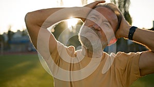 Close up Caucasian European pensioner stretch neck muscles head sporty elderly man warm-up flexibility elastic sunrise