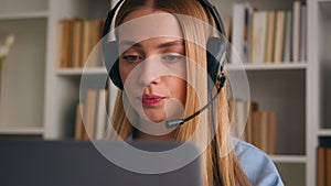 Close up Caucasian female girl office worker in headset conference video calling with laptop computer. Serious woman