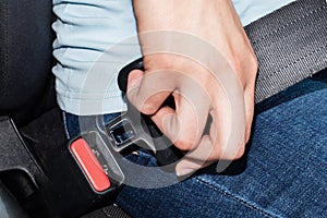 Close-up of a caucasian female hand holding a seat belt buckle for fastening in a car. Car safety concept