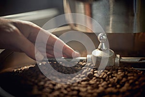 close up of a caucasian hand touching coffee grains in modern machine for mixing