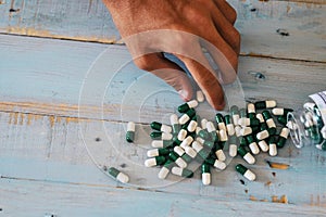 Close up of caucasian man hand taking chemichal pharmacy pills from a blue wood background - concept of drugs and disease - doctor