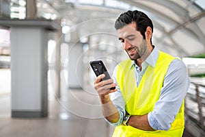 Close up Caucasian man use a smartphone for communicate with his co-worker and for contact with his friend while he wearing yellow