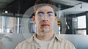 Close-up caucasian serious puzzled clever guy student in glasses looking at camera posing indoors young man with sad