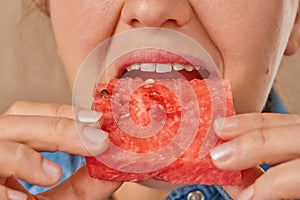 Close-up of a Caucasian woman holding a slice of watermelon with both hands and putting it in her mouth. Front view