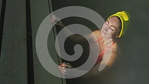 Close up caucasian woman in a swim in hot saline mineral water bath at a traditional spa outdoor with soft magic pink