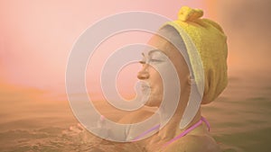 Close up caucasian woman in a swim in hot saline mineral water bath at a traditional spa outdoor with soft magic pink