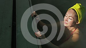 Close up caucasian woman in a swim in hot saline mineral water bath at a traditional spa outdoor with soft magic pink