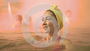 Close up caucasian woman in a swim in hot saline mineral water bath at a traditional spa outdoor with soft magic pink
