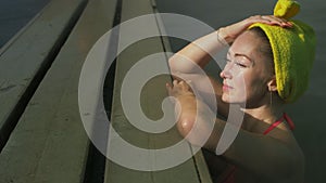 Close up caucasian woman in a swim in hot saline mineral water bath at a traditional spa outdoor with soft magic pink