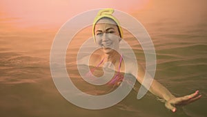 Close up caucasian woman in a swim in hot saline mineral water bath at a traditional spa outdoor with soft magic pink