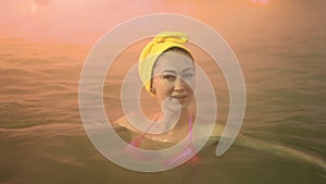 Close up caucasian woman in a swim in hot saline mineral water bath at a traditional spa outdoor with soft magic pink