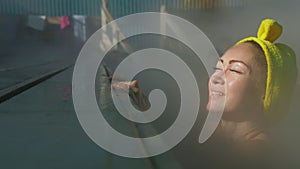 Close up caucasian woman in a swim in hot saline mineral water bath at a traditional spa outdoor with soft magic pink