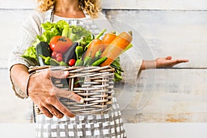 Close up with caucasian woman taking a bucket full of coloured and fresh seasonal vegetables for a healthy and natural food