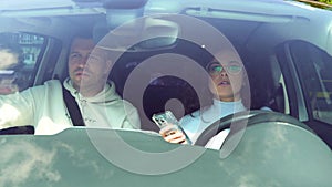 close up of Caucasian young couple man and woman in car. Beautiful attractive stylish female driving a car and tapping