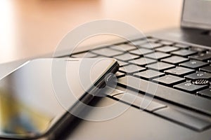 Close up of a cell phone and laptop keyboard, mobile phone and laptop, working at home