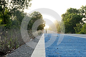 Close up center of blue bike lane on an asphalt road. with blurred of bike look out towards the end of the road.