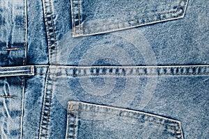 Close up on the center stitching and the back pocket of a blue jeans