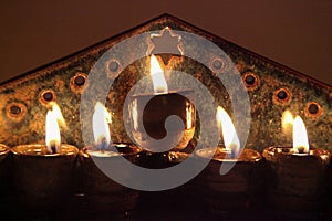 Close-up on ceramic hanukiah lit with 4 candles and shamash