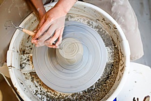 close up of ceramist hands ceramic on the lathe or potter's wheel inside a pottery workshop with natural ligh